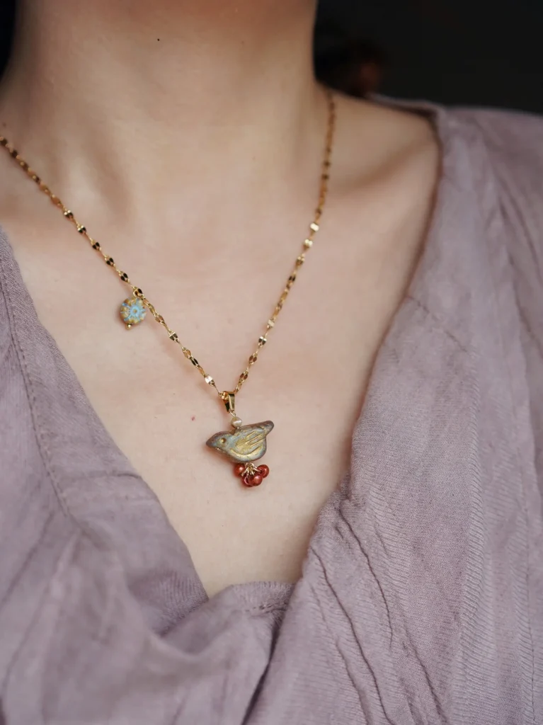 Model showcases a handcrafted bird pendant necklace, highlighting its delicate design and natural charm for elegant layering.