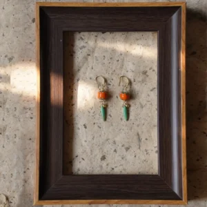 Handcrafted glass bead earrings in bold orange and green create a vibrant vintage contrast.