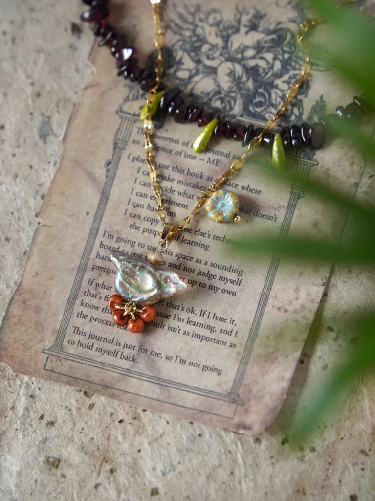 handmade garnet vintage necklace with a blue bird pendant, creating a romantic, nature-inspired look full of poetic charm.
