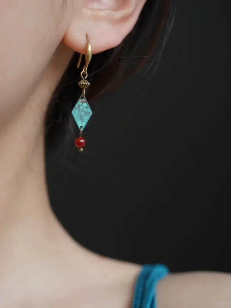 Green patina handmade brass earrings worn by model reflect artisan texture while enhancing everyday outfits with rustic charm.