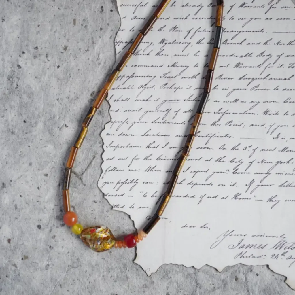 Handmade gemstone necklace with glass beads and warm-toned natural stones styled in earthy palette.
