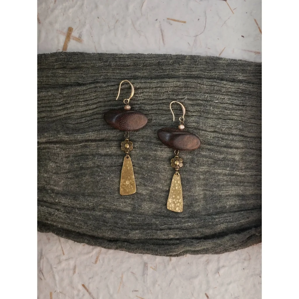Handmade vintage Zen earrings made of brass and wood beads, resting on a cozy knitted sweater