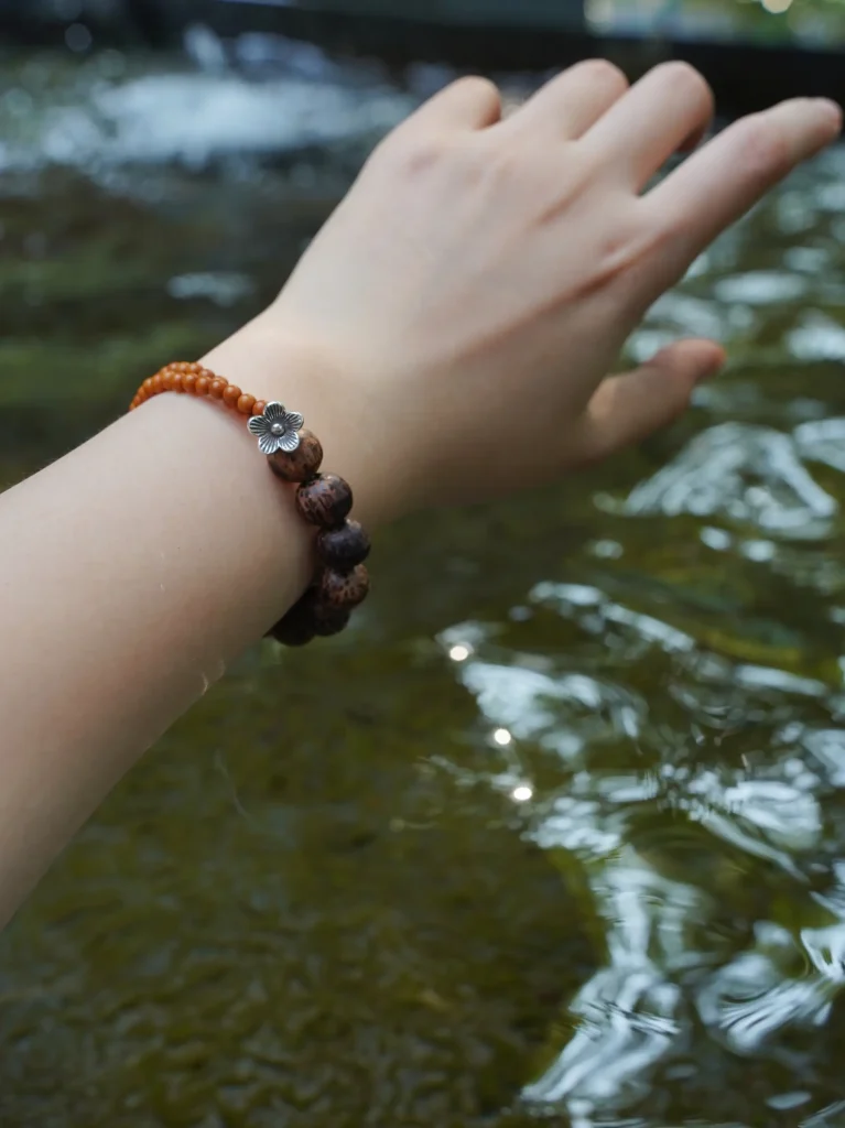 Model wears a coconut wood and olive pit beaded bracelet that showcases natural texture and handcrafted character