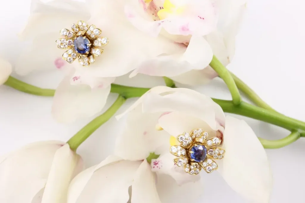 Retro-style diamond and sapphire stud earrings, showcasing intricate craftsmanship and design with gold and small gemstones.