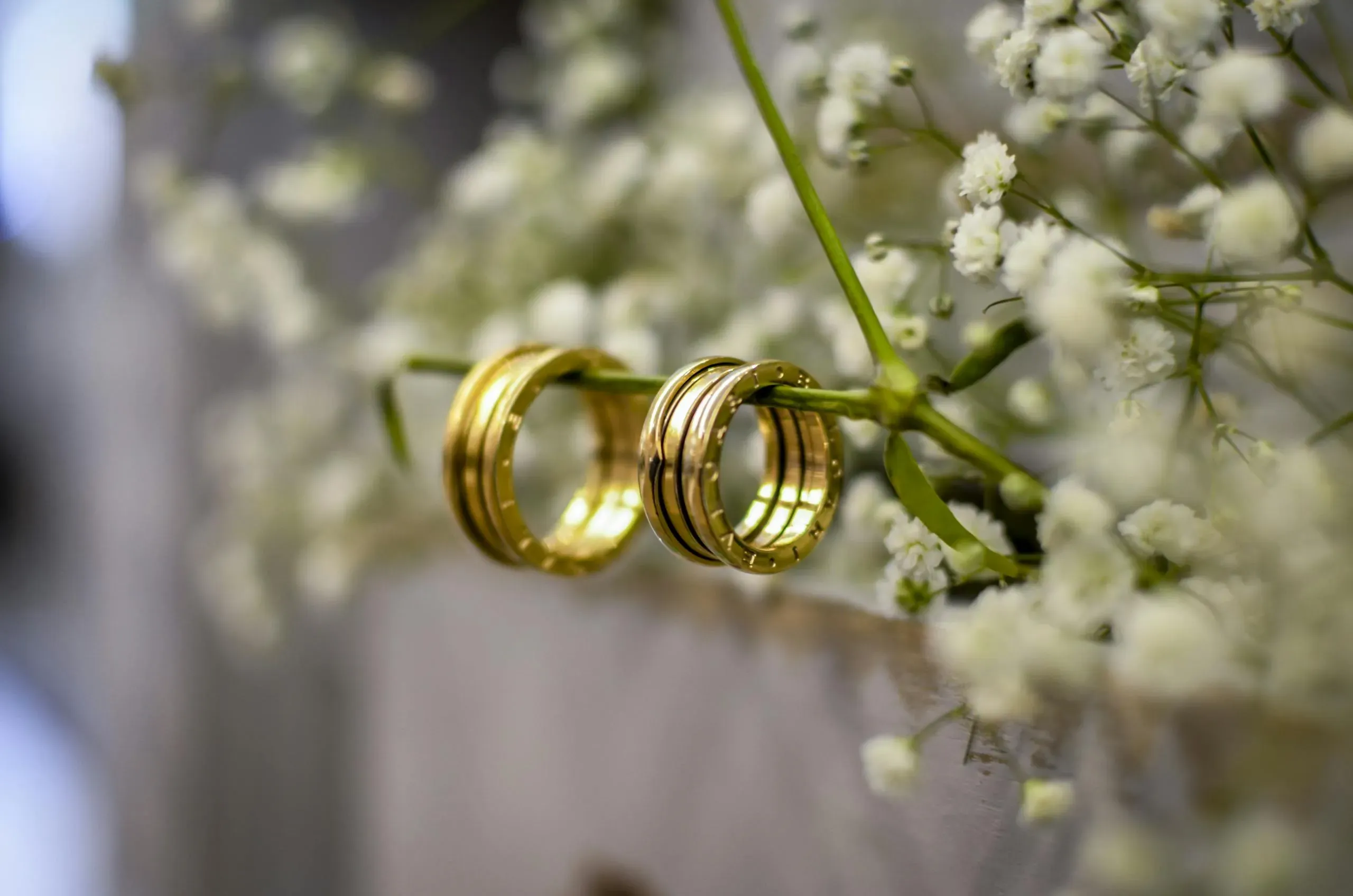 Shimmering gold wedding bands resting on baby’s breath flowers, symbolizing eternal love and commitment.