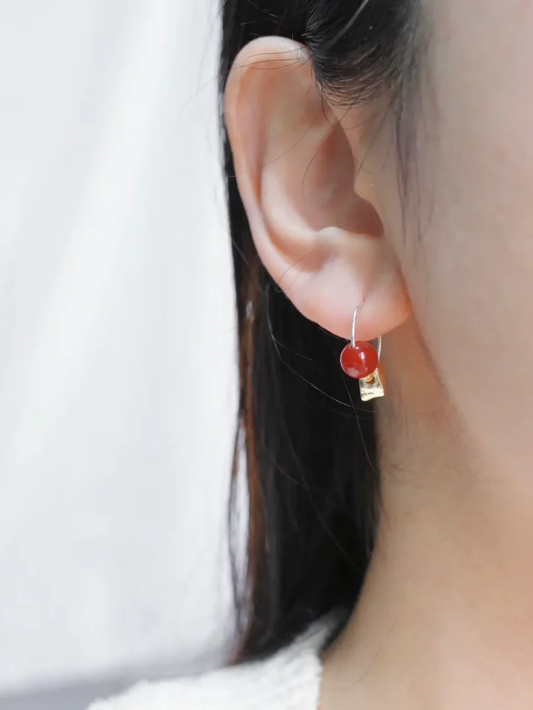 Model showcases red agate earrings, highlighting their delicate charm and versatile style.