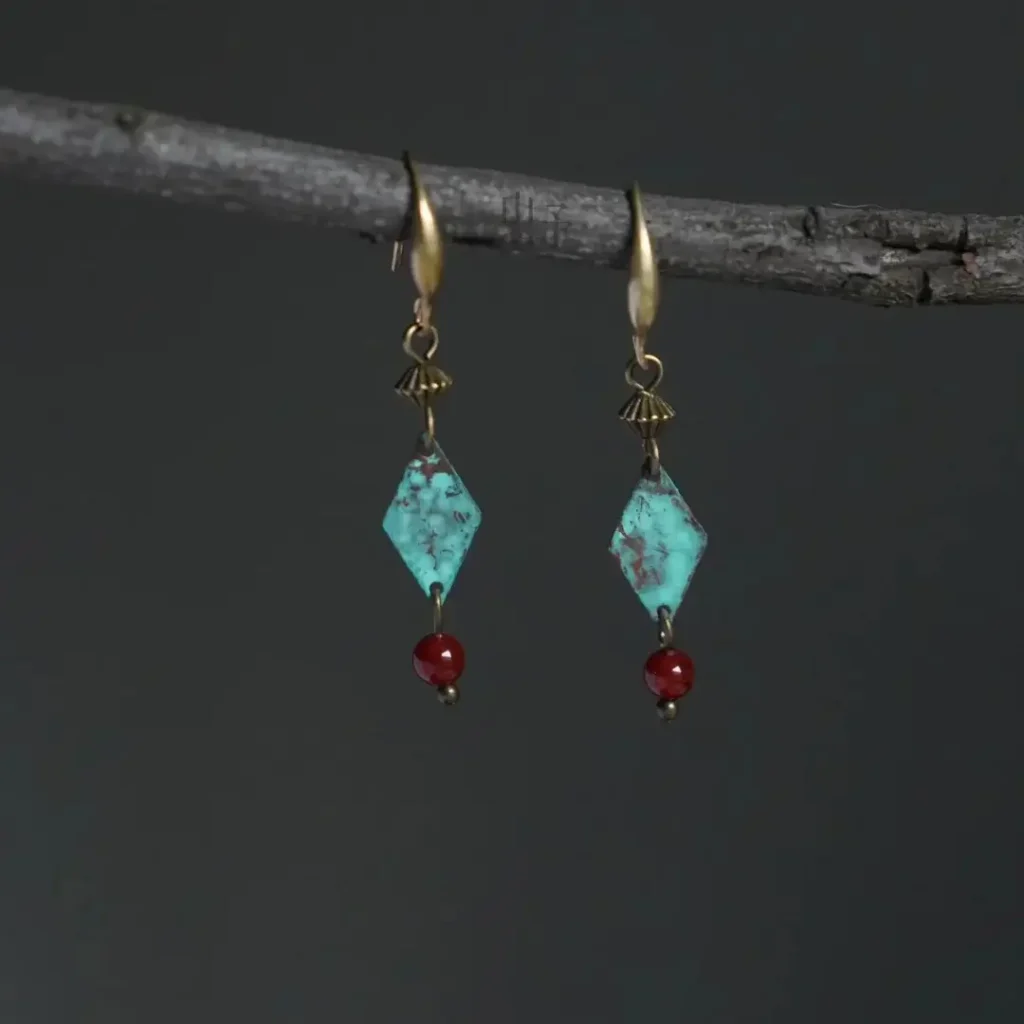 Handmade patina brass drop earrings with elongated pendant design in vintage style.