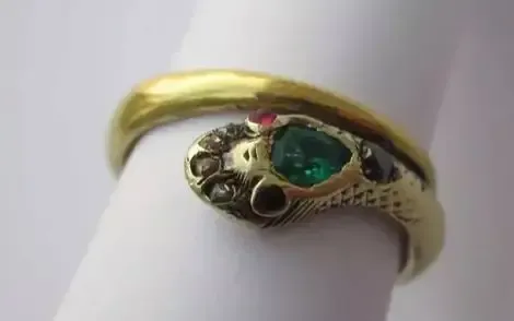 An illustration of Queen Victoria's engagement ring, gifted by Prince Albert in 1840, designed as a serpent symbolizing eternal love, with a round emerald as the centerpiece.