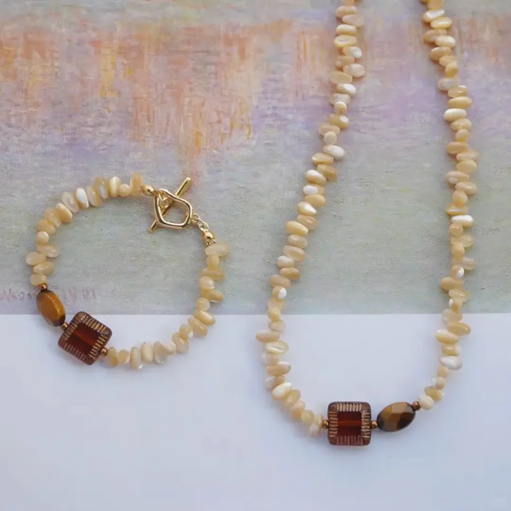 Handmade seashell necklace and bracelet set with tiger's eye on impressionist background.