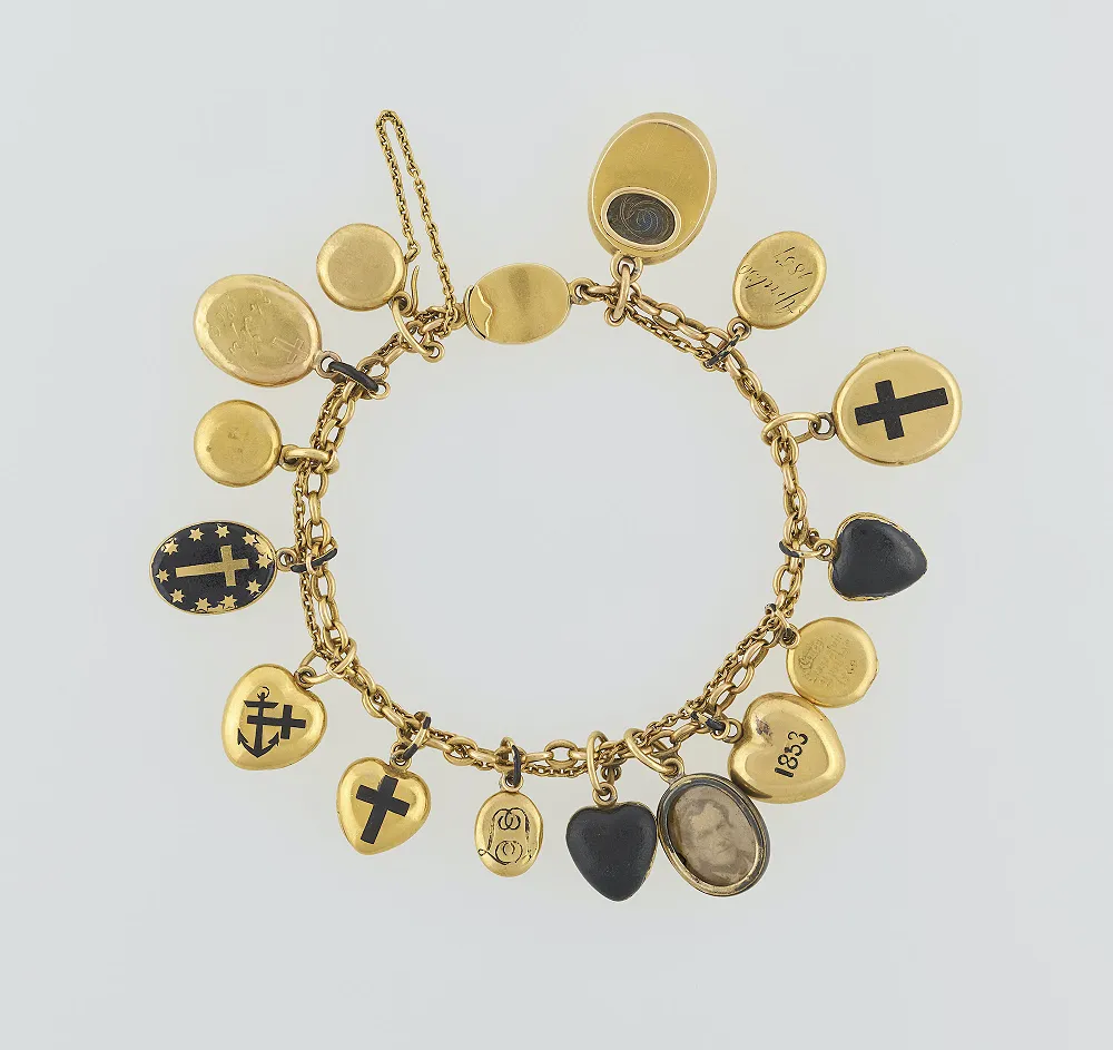 Illustration of Queen Victoria's iconic charm necklace, featuring enamel boxes containing her children's hair and a pendant with an inscription and miniature photo of Prince Albert.