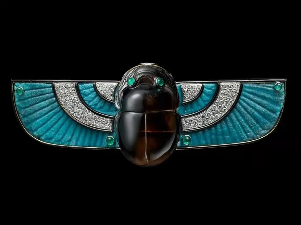 Illustration of a sacred scarab ceramic brooch, featuring a smoky quartz scarab with diamond, emerald, and ceramic accents in an Art Deco style.