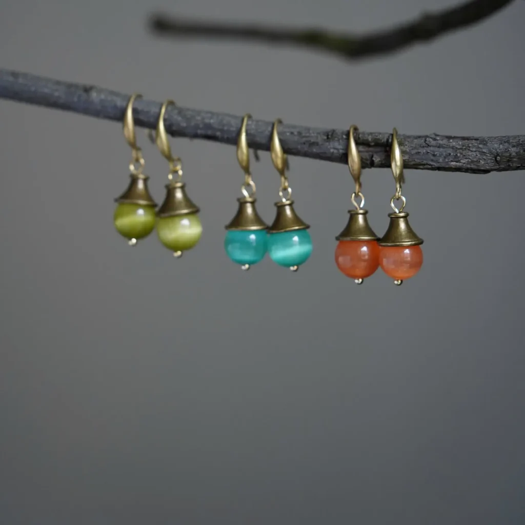 Handmade earrings with Cat’s Eye stones in green, orange, and blue - a vintage-inspired trio of light and charm