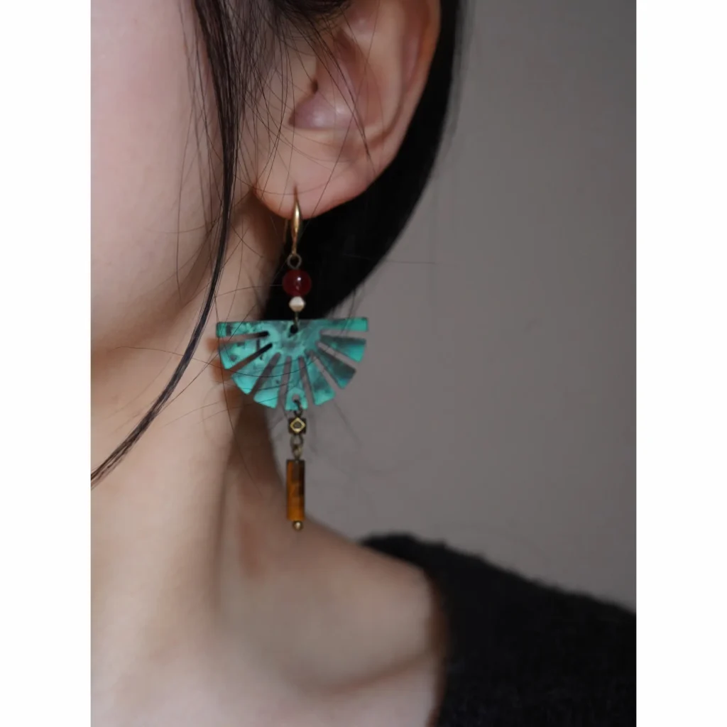 Model wearing fan-shaped oxidized brass earrings with red agate and tiger's eye beads, bohemian style handmade jewelry.