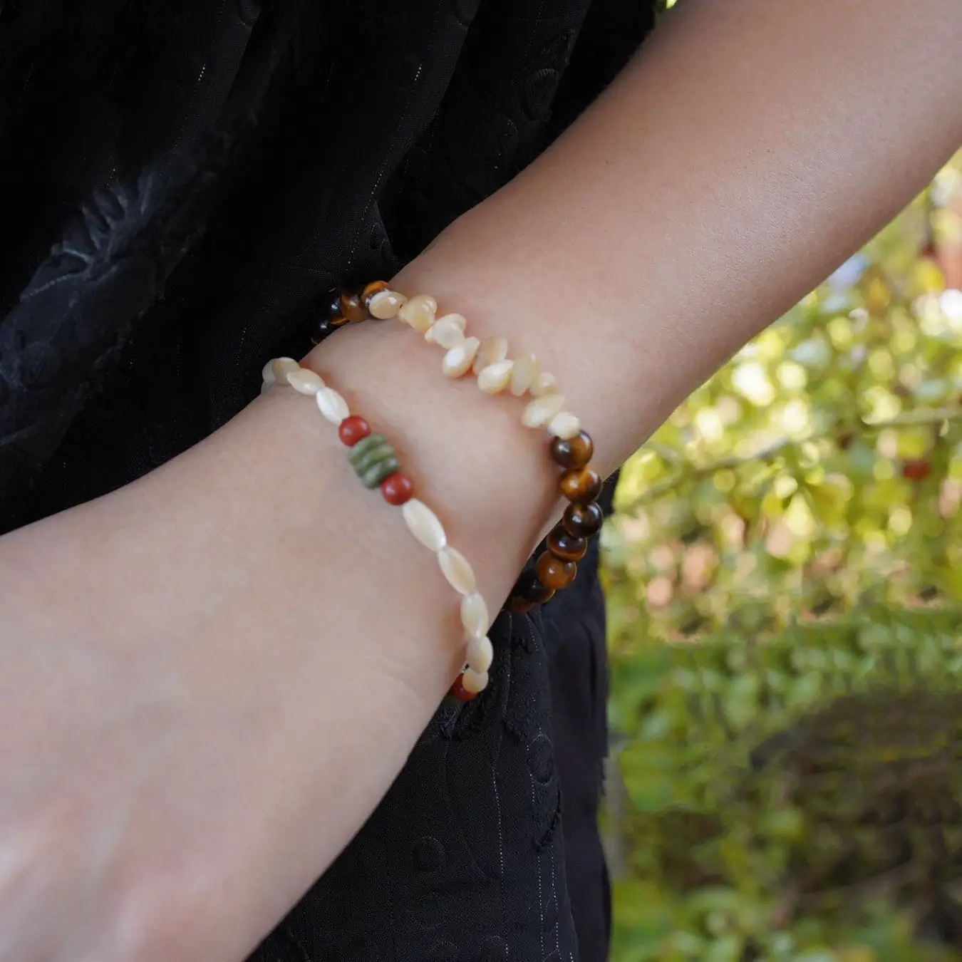 Delicate natural shell bracelets are stacked to showcase layered styling and versatile handmade design for everyday wear.