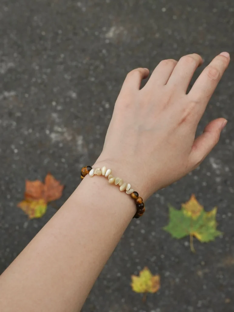 Handmade bracelet worn under natural sunlight, highlighting its polished textures and elegant design.