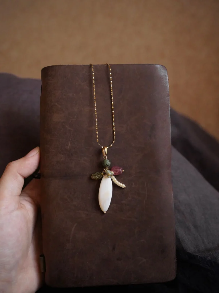 Pendant showcases natural freshwater pearls, volcanic stones, Czech beads, and seed beads, creating a handcrafted, elegant detail.