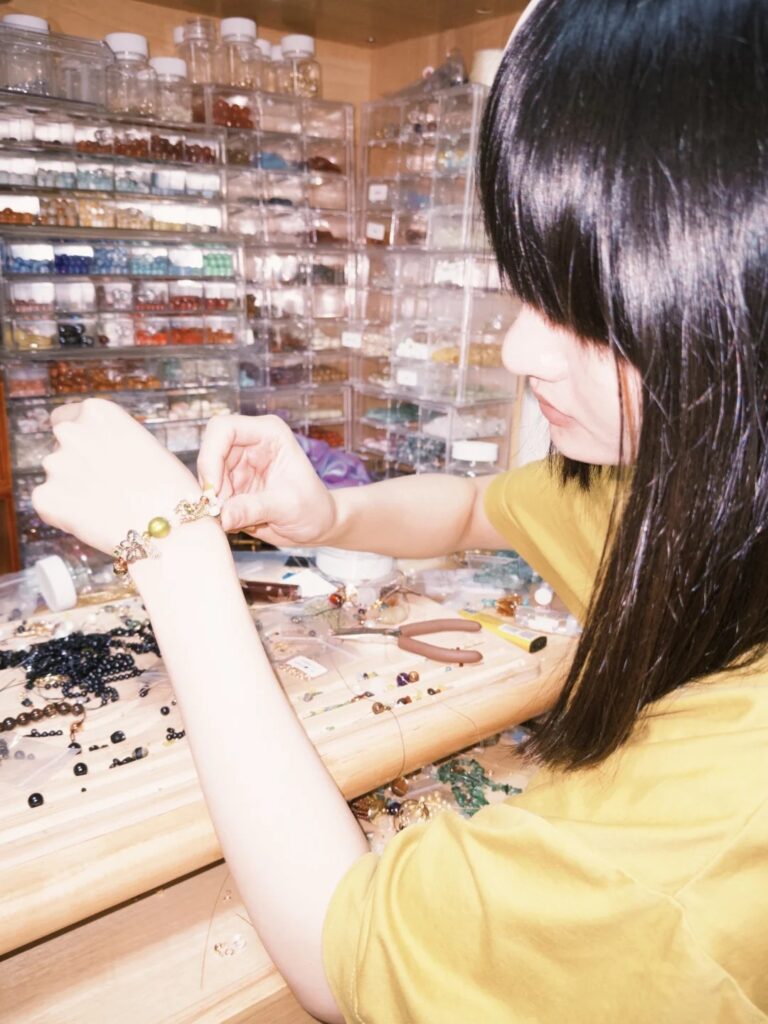 Artisan jeweler working at a cluttered workbench filled with beads and jewelry components