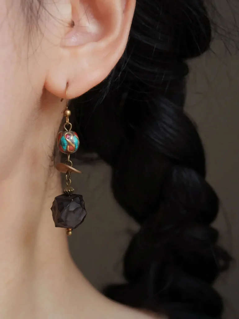 Close-up of a single Jewea earring, featuring ebony wood with turquoise and agate inlays.