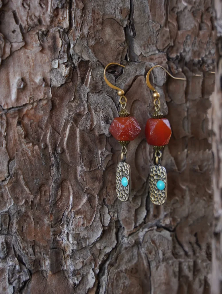 Handcrafted vintage-style agate earrings with hammered brass displayed on a tree branch for natural presentation.