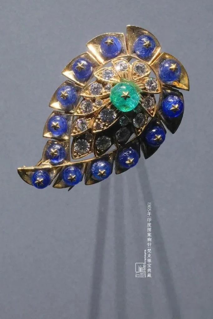 A vintage handmade brooch from 1965 featuring intricate floral, vine, and geometric patterns inspired by traditional Indian designs, with rich colors for a classic, exotic feel.