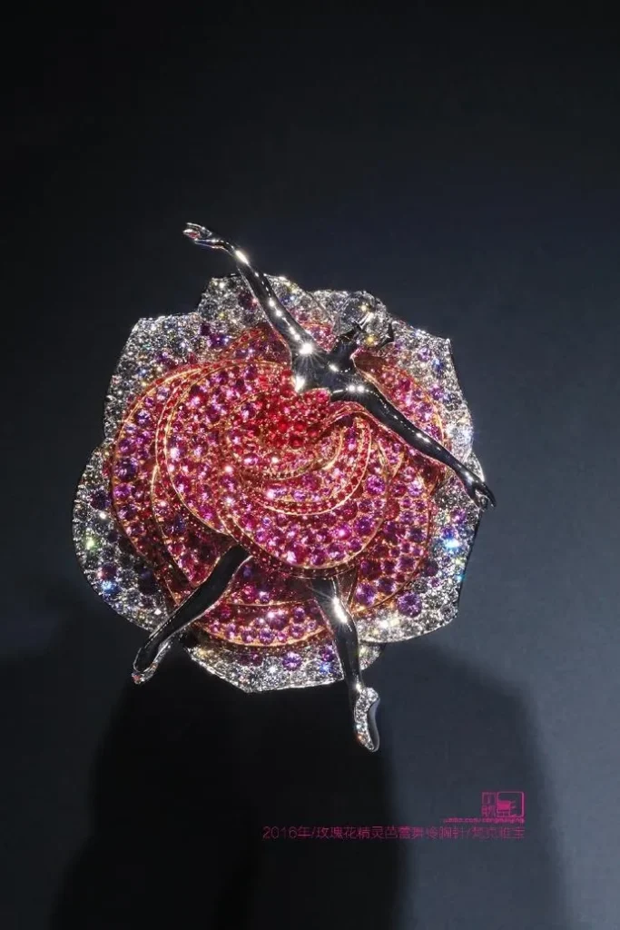 An illustration of the Van Cleef & Arpels 2016 Rose Fairy Ballerina brooch. The piece depicts a ballerina wearing a skirt made of rose petals, set with diamonds, rubies, or pink sapphires. The design blends the elegance of ballet with the romance of flowers, creating a whimsical and poetic piece.
