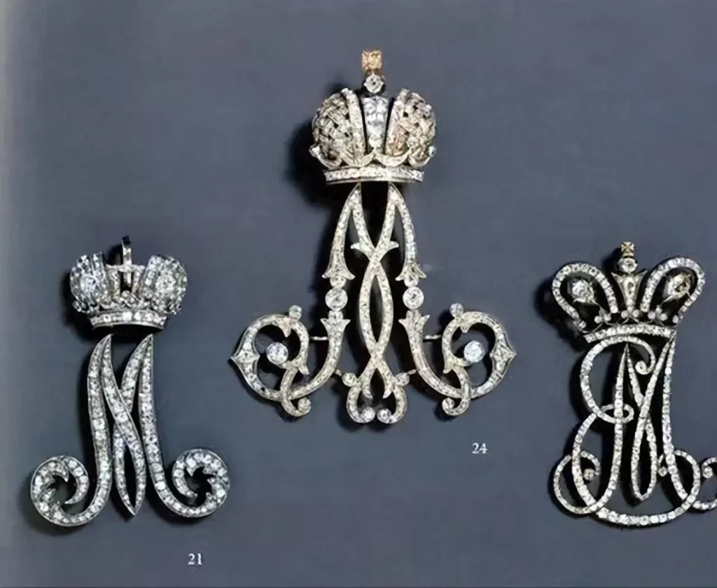 A vintage handmade brooch featuring the monogram of Russian Empress Maria, with a royal emblem or interwoven letters possibly set with diamonds or precious gems, symbolizing royal dignity and authority.