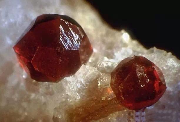 Two almandine garnet gemstones with deep red to brownish-red hues from the garnet family gemstone guide