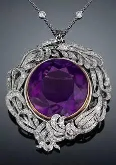 A two-tone gold and silver brooch that can also be worn as a pendant, centered with a purple amethyst.