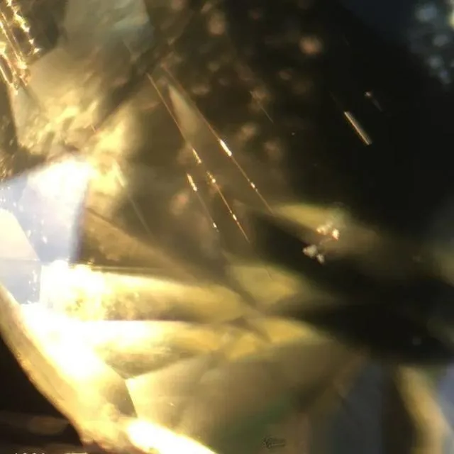 An image of rutile needles inside a regular chrysoberyl gemstone. These needles are slender, internal crystal inclusions that do not form a cat's eye effect due to their small number or irregular arrangement.