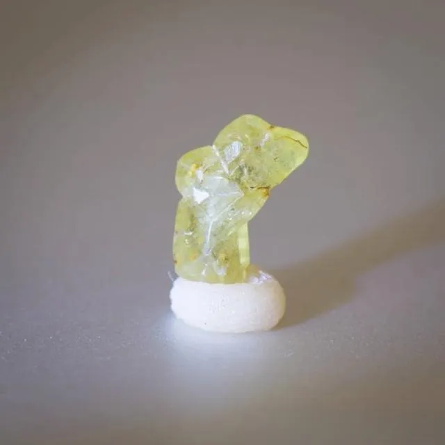 An image of a curved columnar chrysoberyl crystal specimen. The crystal has a distinct curved shape, a yellowish-green color, and represents a rare and unique crystal habit formed during the natural growth of chrysoberyl.