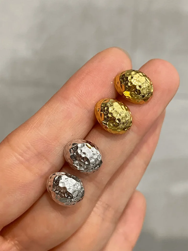 Gold and silver 925 silver earrings displayed in hand under natural light, showing hammered shine.