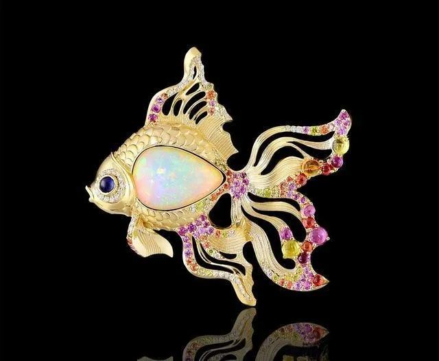 An intricate goldfish-shaped pendant with a gemstone inlay, showcasing creative and detailed animal jewelry design.