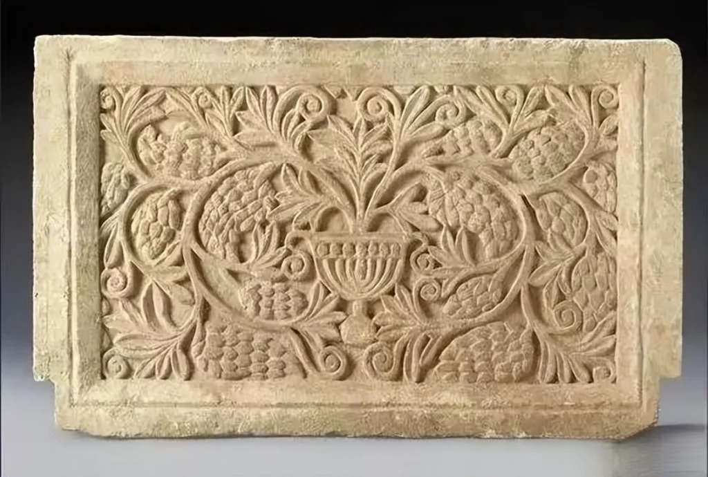 An illustration of a graceful and intricate pattern featuring curling grapevines and foliage, with clusters of grapes interspersed throughout the design.