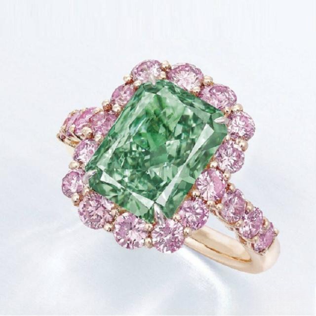 A fancy colored diamond ring featuring a large green diamond center stone surrounded by pink diamond accents.
