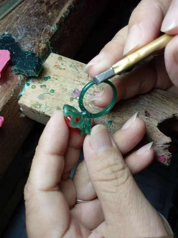 An artisan hand-carving a detailed wax model for a custom jewelry piece using specialized tools.
