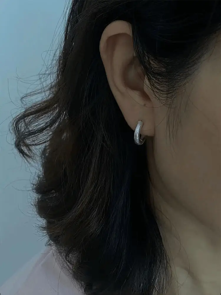 Front view of handcrafted silver hoop earrings worn to show minimalist design and comfortable fit.