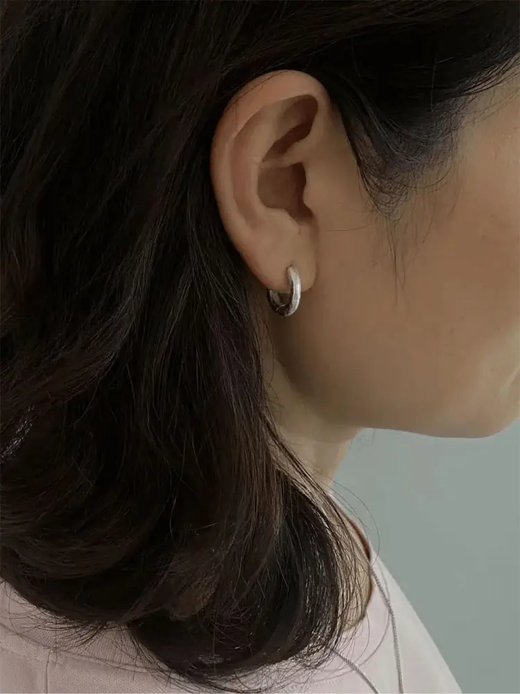 Side view of handcrafted silver hoop earrings worn to show minimalist design and comfortable fit.