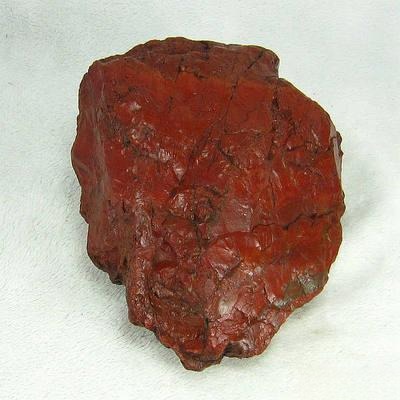 Large rough Red Jasper stone, highlighting Jasper vs Nephrite Jade differences, with brownish-red color and hematite inclusions.
