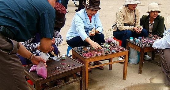 Local women arranging gemstones on stools at Luc Yen gemstone market in Vietnam.