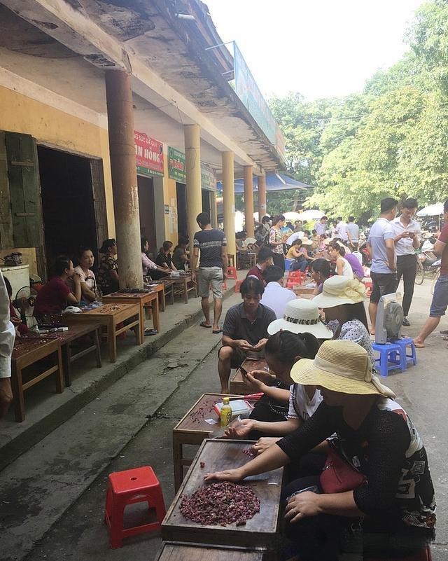 Local women selling rough gemstones and small fragments at Luc Yen gemstone market on stools and mats.