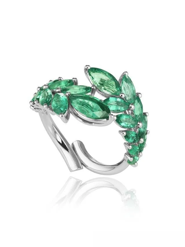 An illustration of a luxury style gold diamond ring. The ring's main design is a floral branch, with leaves formed by multiple marquise-cut emeralds. The center of the flower is set with a large main diamond, creating a magnificent and vibrant design with an elegant color palette.