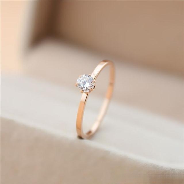 Close-up of a minimalist prong-set diamond engagement ring showing subtle metal texture and elegant design