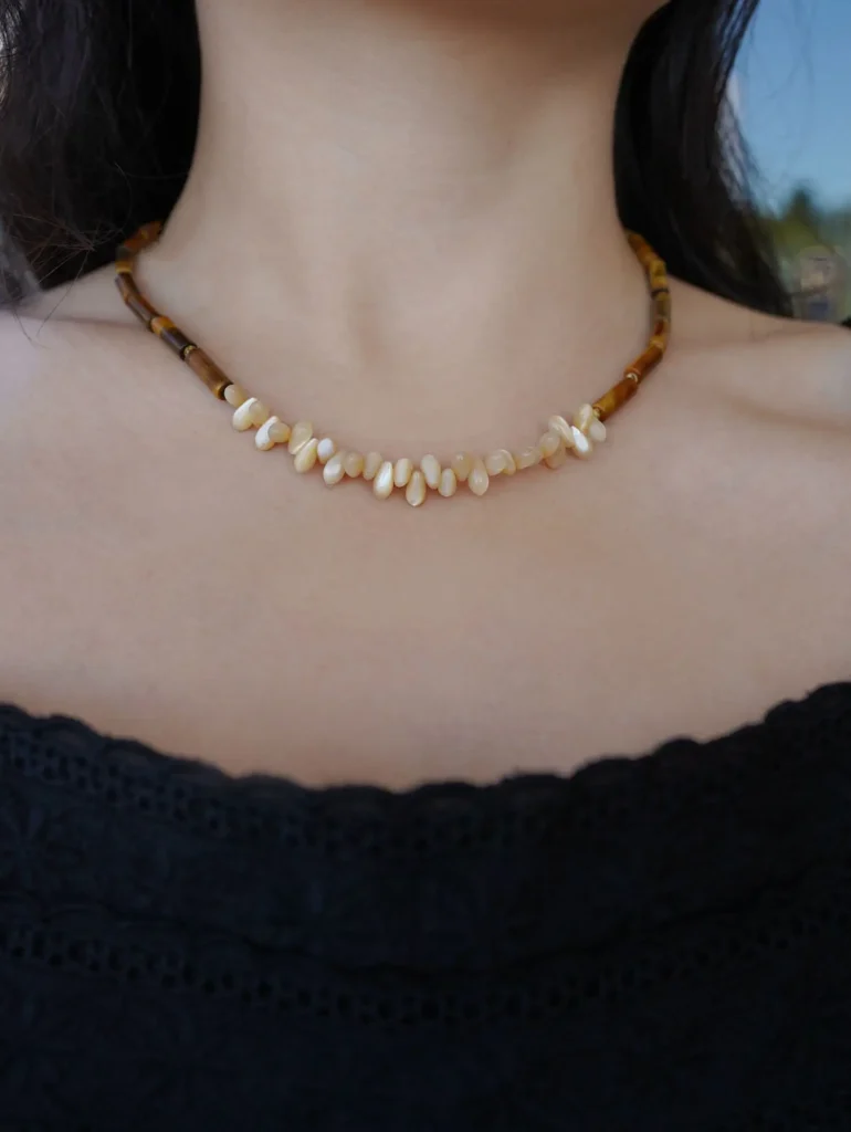 Model wears the tiger eye and conch shell necklace, showcasing its design, texture, and everyday wearable style.