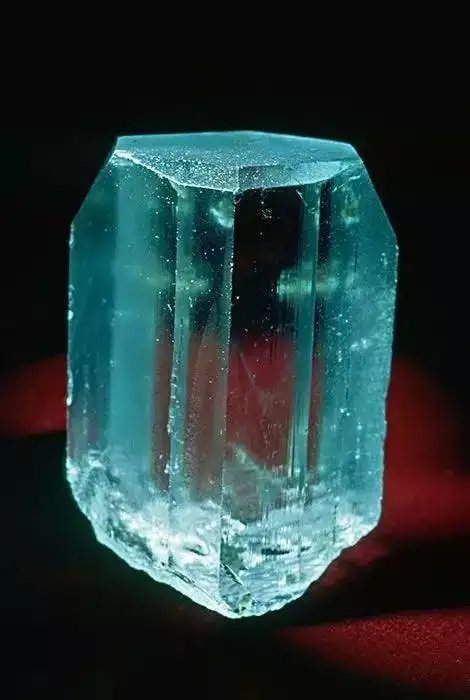 A natural, uncut blue topaz rough stone, showcasing its raw crystal form and beautiful pale blue color.