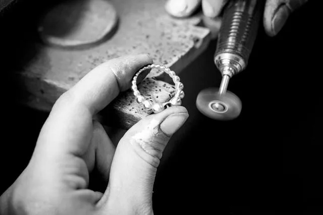 An illustration showing the detailed polishing process for a jewelry metal surface, depicting a jeweler using tools to create a brilliant and smooth finish.