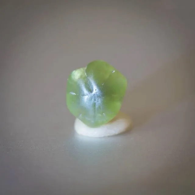 An image of a pseudo-hexagonal triple-twinned chrysoberyl crystal. The specimen is formed by three interpenetrating crystals, creating a false hexagonal shape. It typically displays a yellowish-green or brownish-yellow color and is a classic twinning habit for chrysoberyl.