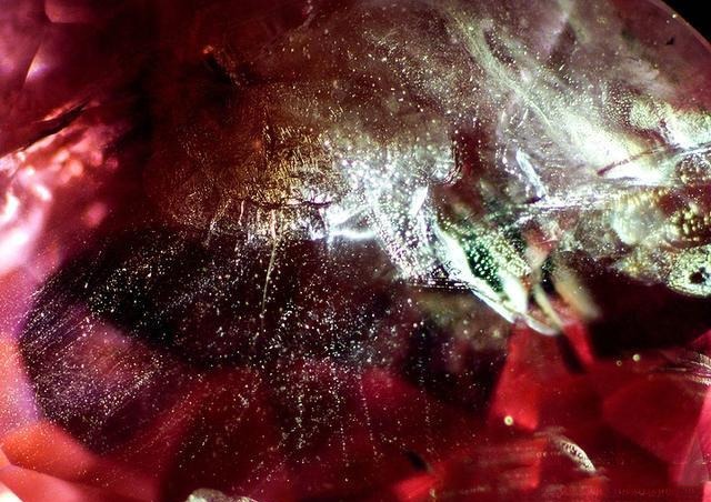 Vietnam Pink Sapphires under a microscope showing countless tiny dot-like liquid and gas inclusions densely distributed throughout the gemstone