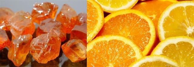 Spessartine garnet gemstone displayed next to a fresh orange showing similar vivid orange color in the garnet family gemstone guide