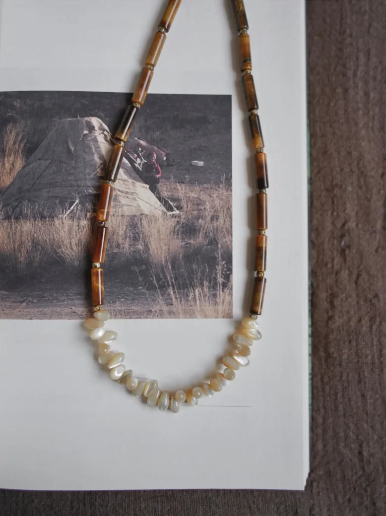This tiger eye and conch shell necklace combines artisan craftsmanship with versatile everyday wear for subtle elegance.