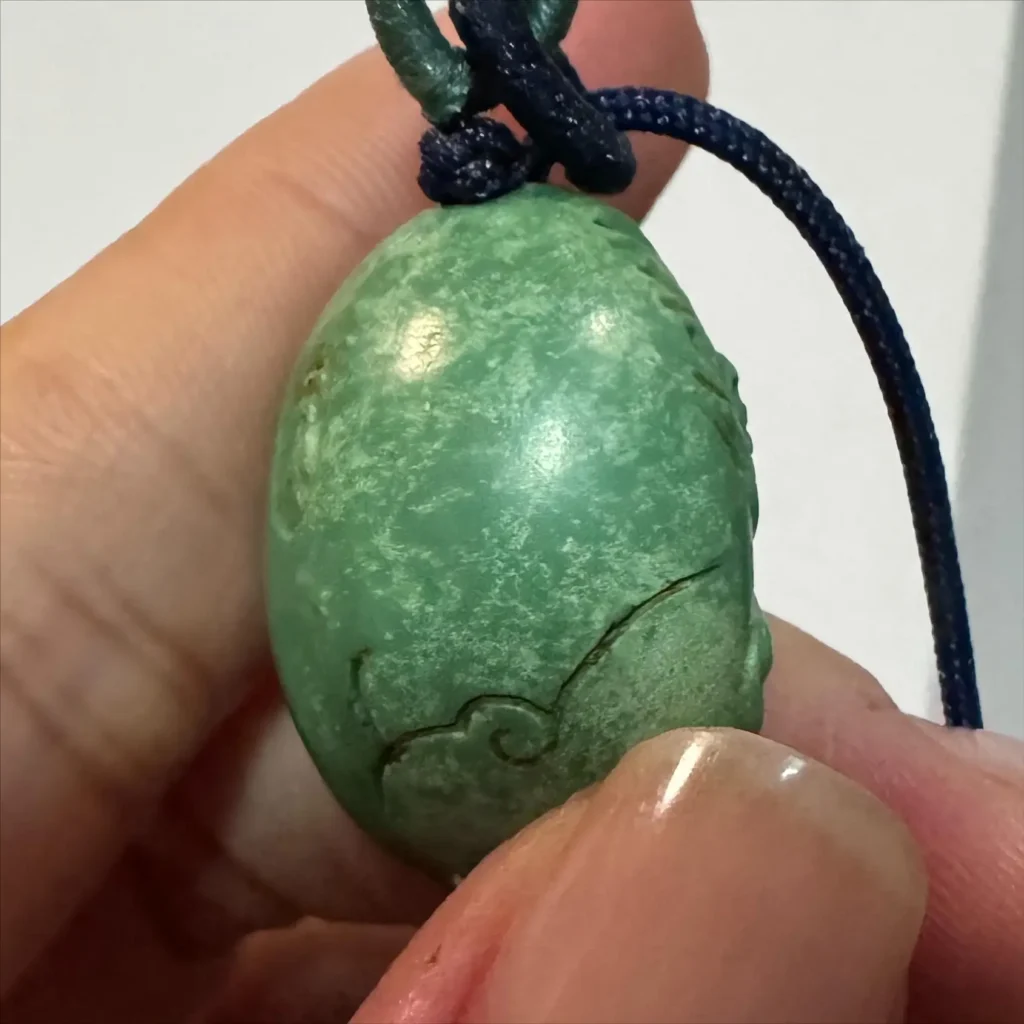 A close-up photograph of a turquoise pendant with visible white spots, highlighting the common issue of Turquoise White Spots faced by wearers.